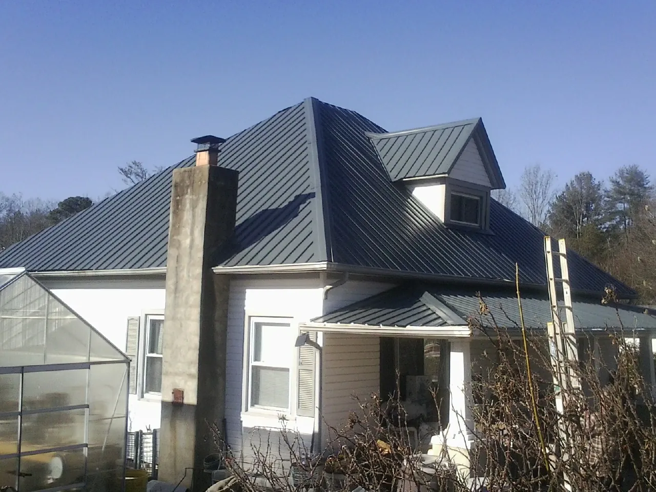 Dark blue standing seam metal roof on a white farmhouse with dormer — Slate & Tile Roof Repair by Roofing Brothers in Ben Lomond