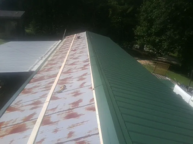 Old rusted panels beside newly installed green metal roofing — Wind Damage Roof Repair by Roofing Brothers in Ben Lomond