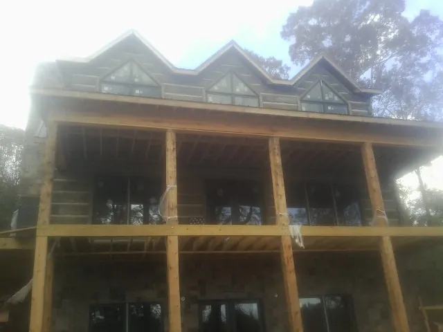 Dormers and porch framing on a large log home under construction — Roof Coating work by our crew in Ben Lomond