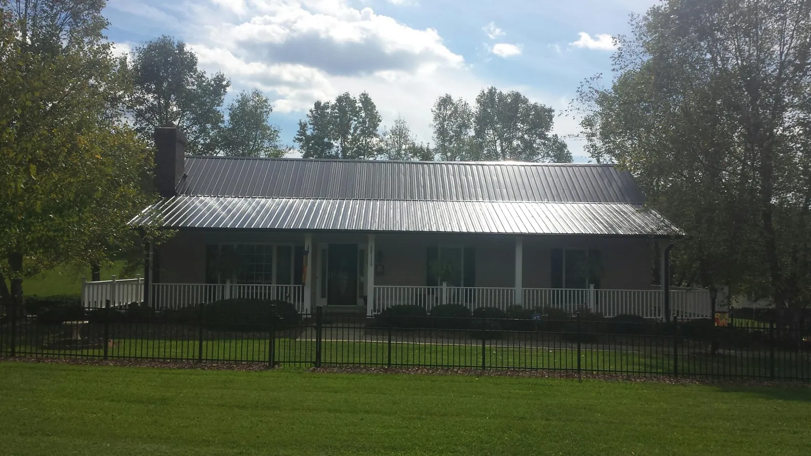Gray metal roof on a brick ranch with a full width front porch — Gutter Guard Installation work by our crew in Ben Lomond