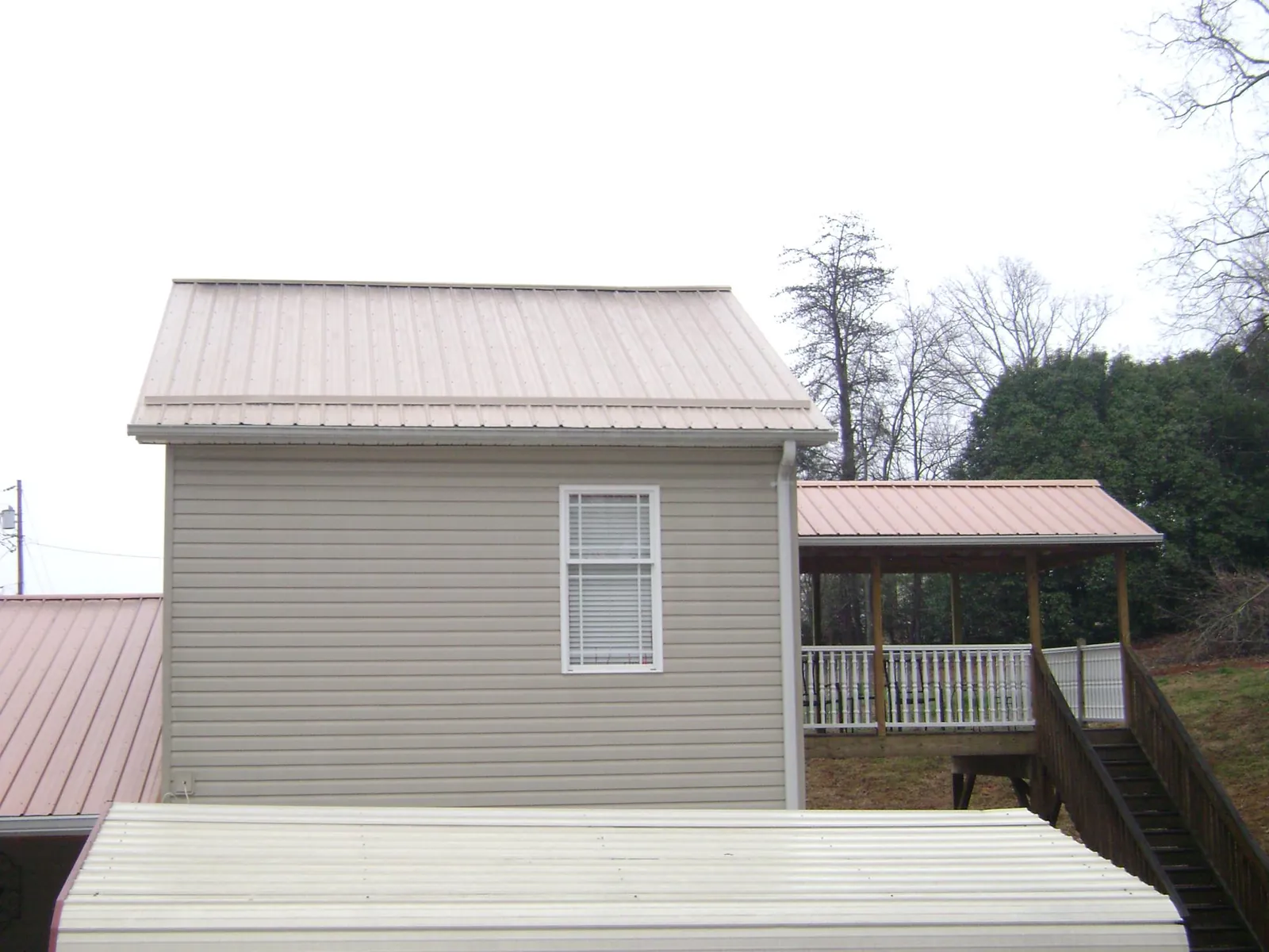 Tan metal roofs on a two story addition and attached porch, from a Roof Replacement job in Ben Lomond