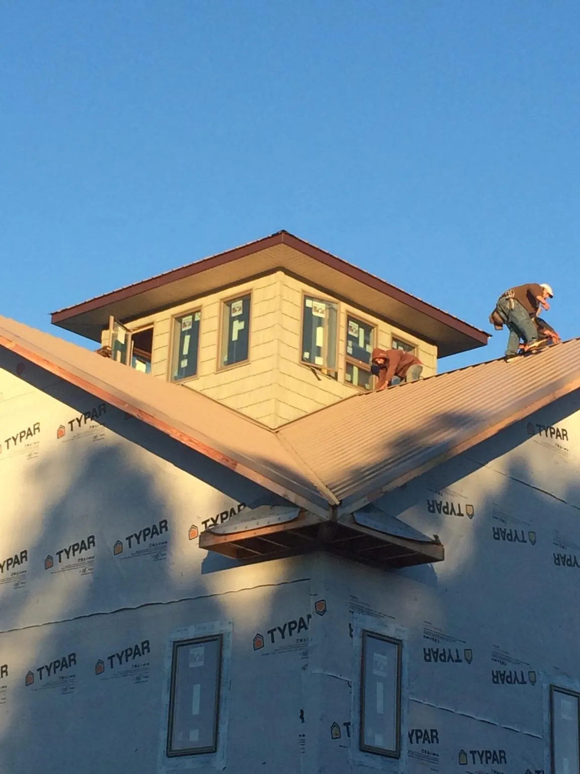 Roofers working around a rooftop cupola on a new metal roof at sunset — Roof Waterproofing in Ben Lomond by Roofing Brothers